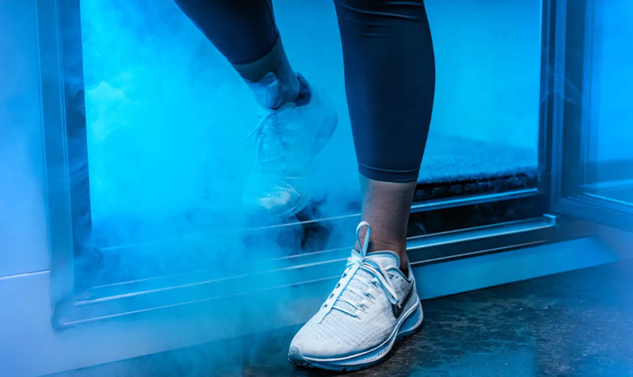 Person in white sneakers stepping out of a door into blue fog or mist.
