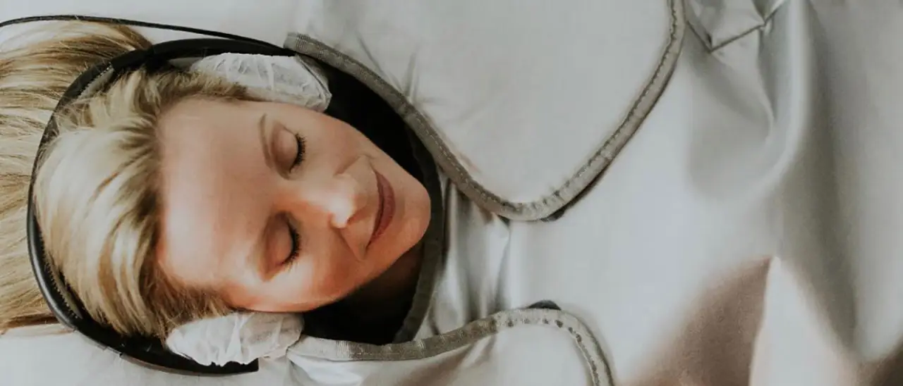 Person relaxing with headphones, eyes closed, wrapped in a cozy blanket.