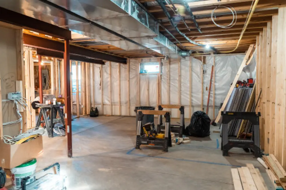 Unfinished basement under construction with exposed framing, tools, and building materials.