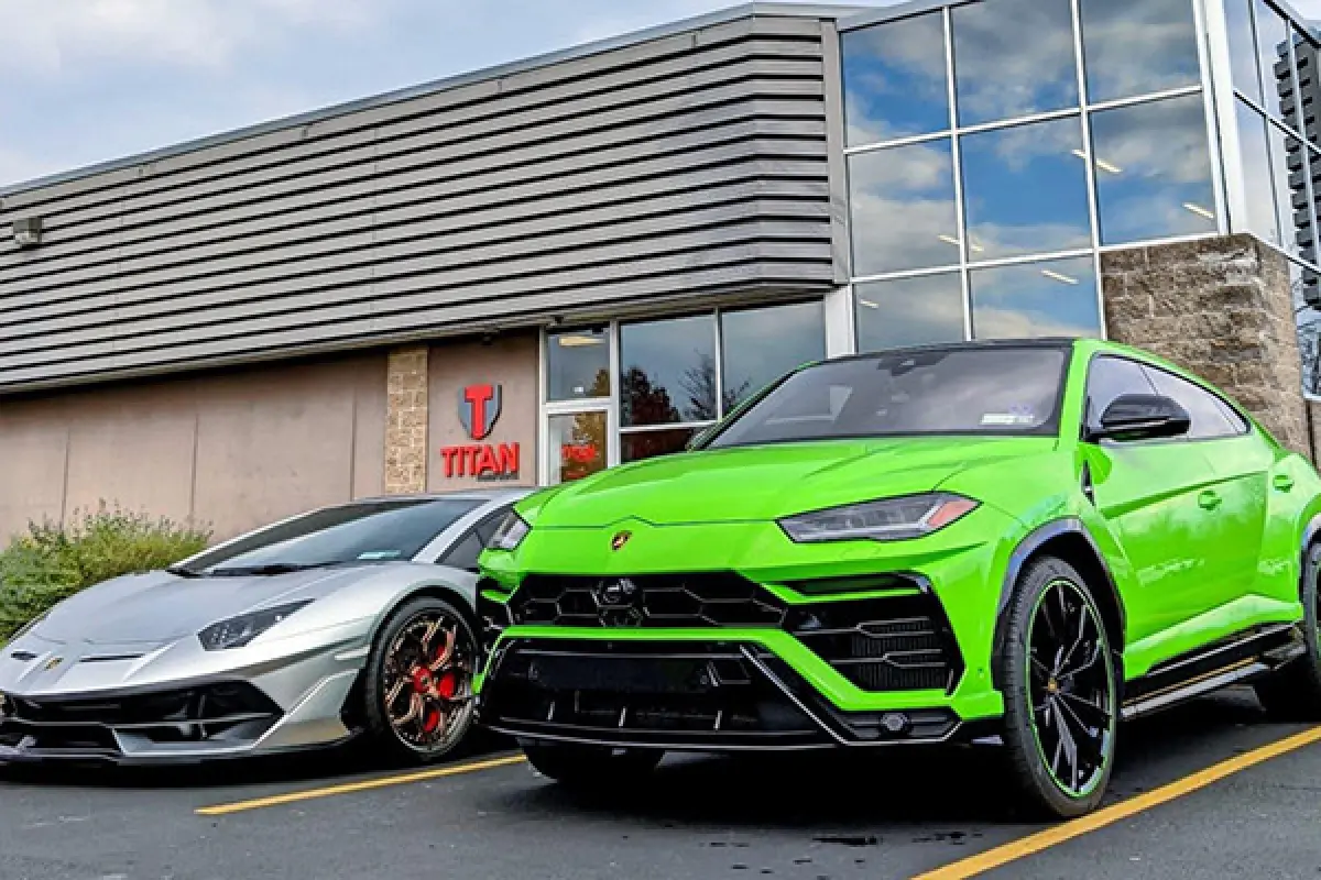 A green Lamborghini SUV and a silver sports car parked in front of a building.