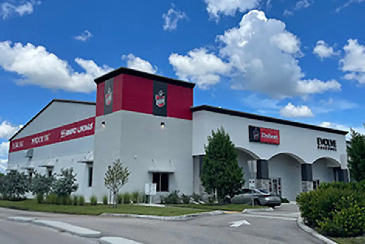 Large building with a bold red and white exterior under a blue sky with clouds.