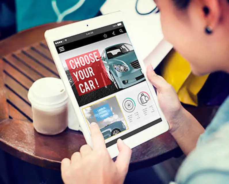 Person browsing cars on a tablet, with CHOOSE YOUR CAR displayed on the screen.