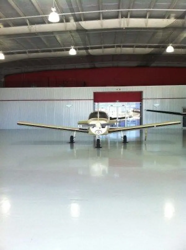 Small single-engine airplane parked inside a clean, spacious airplane hangar.