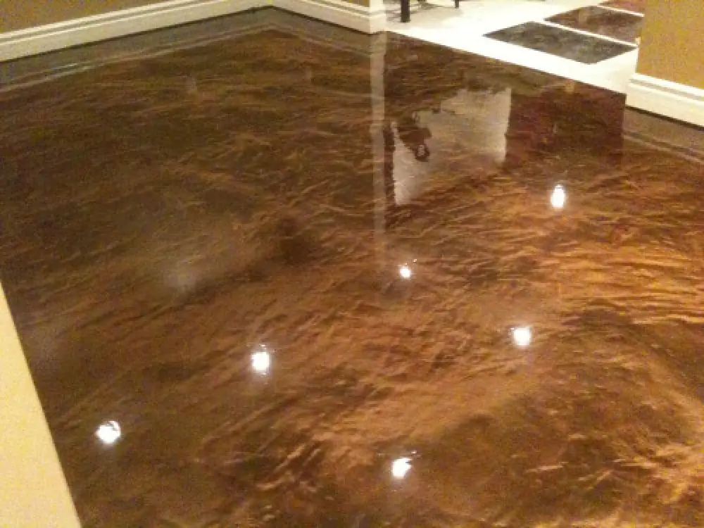 Glossy brown epoxy floor with a marbled effect, reflecting ceiling lights in a room.