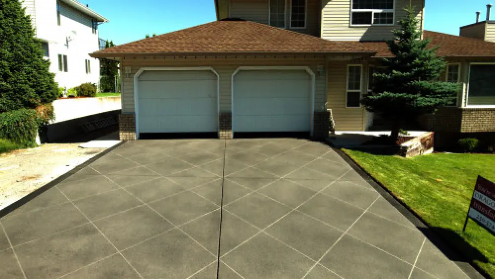 Two-car garage house with a patterned concrete driveway and green lawn.