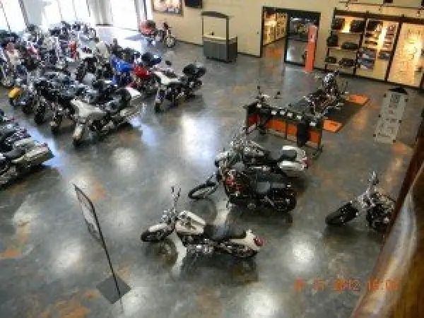 Indoor motorcycle showroom with various bikes displayed on a polished floor under bright lighting.
