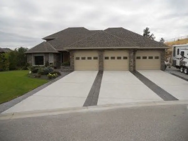 Large modern house with three-car garage, stone accents, and a wide concrete driveway.