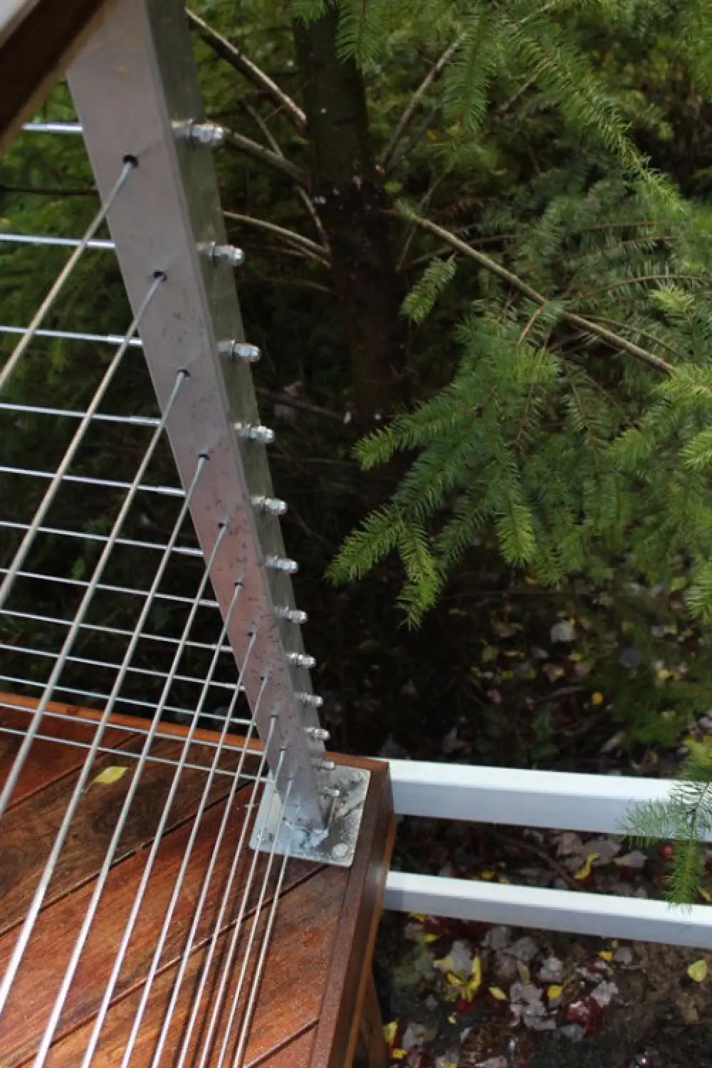 Acorn nuts cap cable railing terminals on an angled metal post.