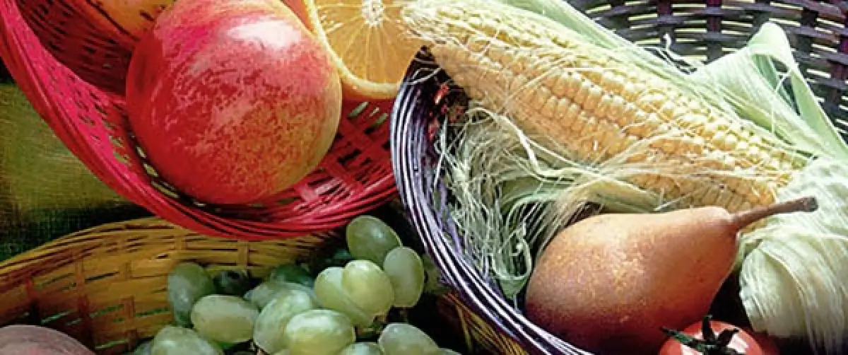 assorted fruits and vegetables in colorful baskets, including corn, grapes, a pear, and apples