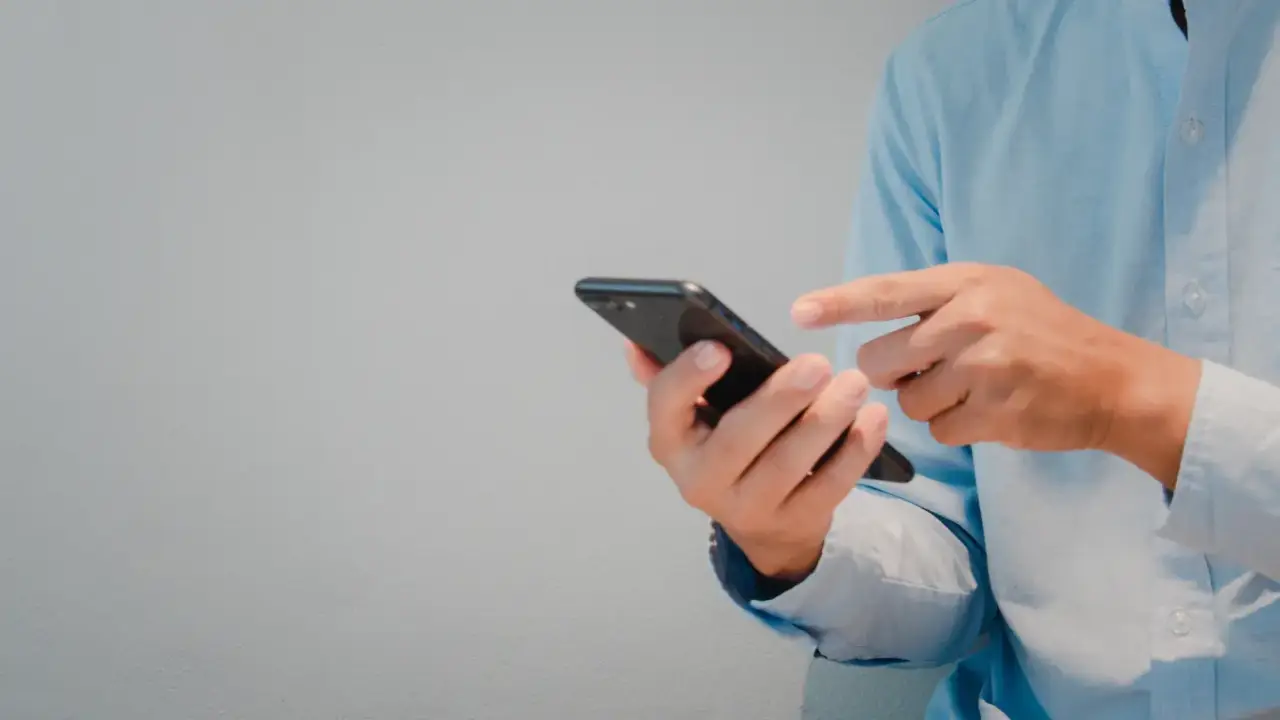 man in blue button up texting on a phone