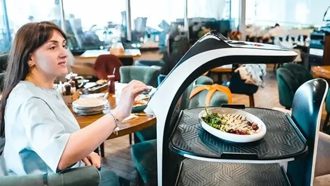 woman grabbing her food order from food service robots