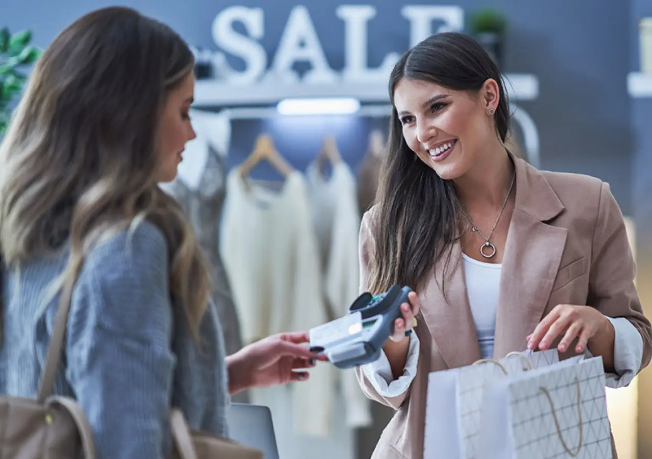 womn uses tap-to-pay to smiling store worker dressed in a blazer