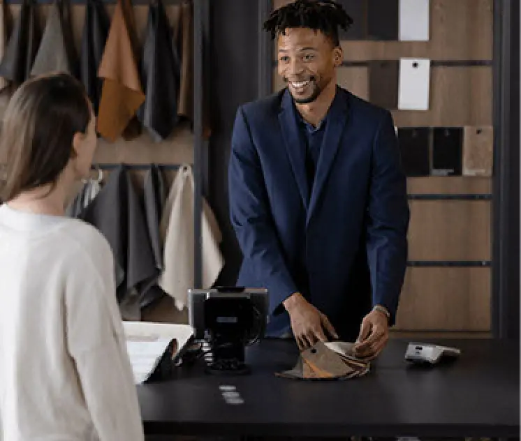 man in dark blue suit cashes out woman at register