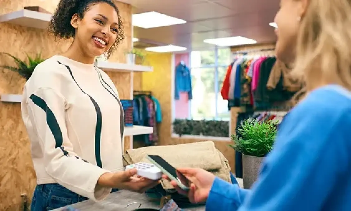 customer pays with phone to a smiling sales associate