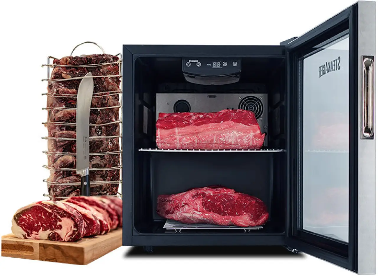Steaks aging inside an open SteakAger with beef cuts beside it.