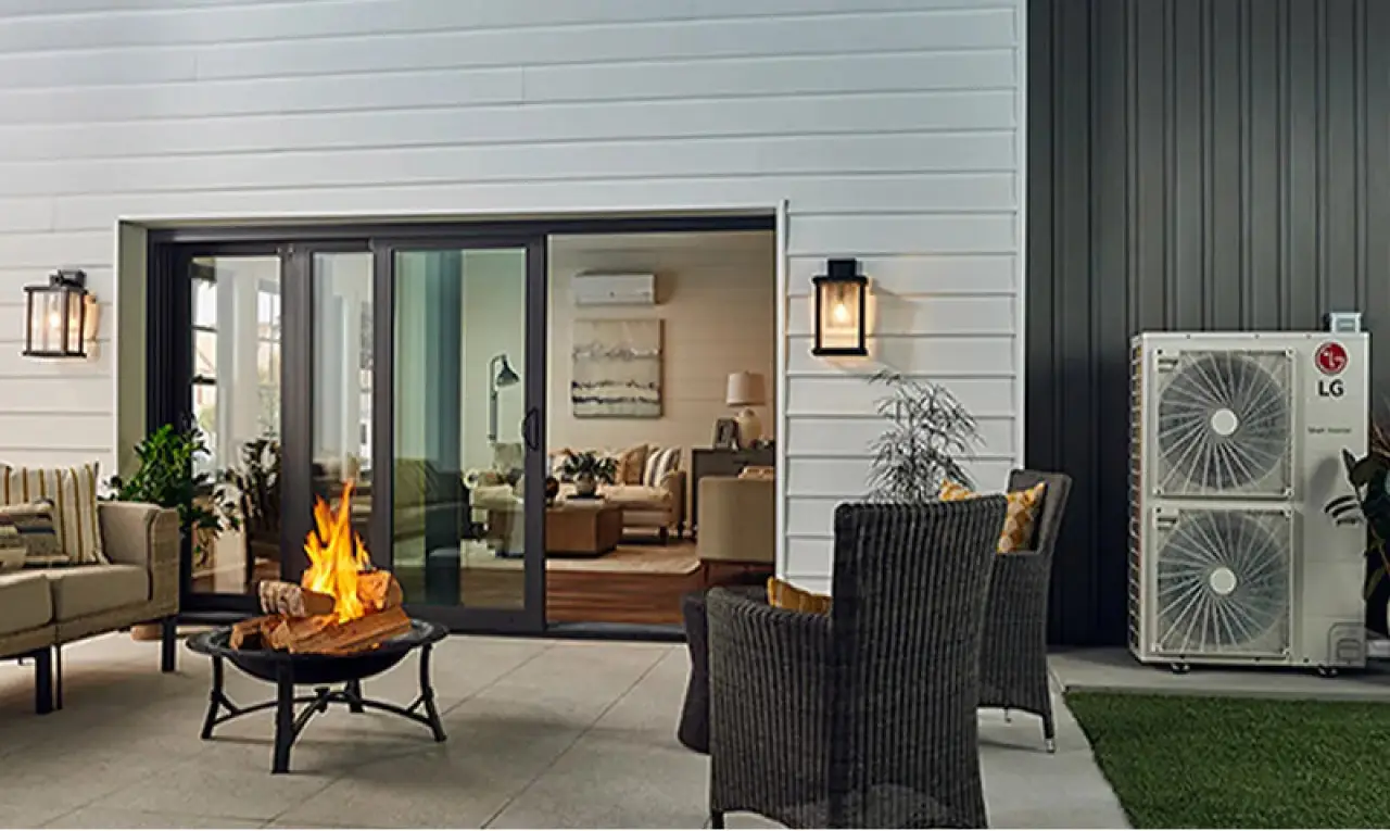 Patio with wicker chairs, fire pit, and sliding doors to a cozy living room, LG unit outside.