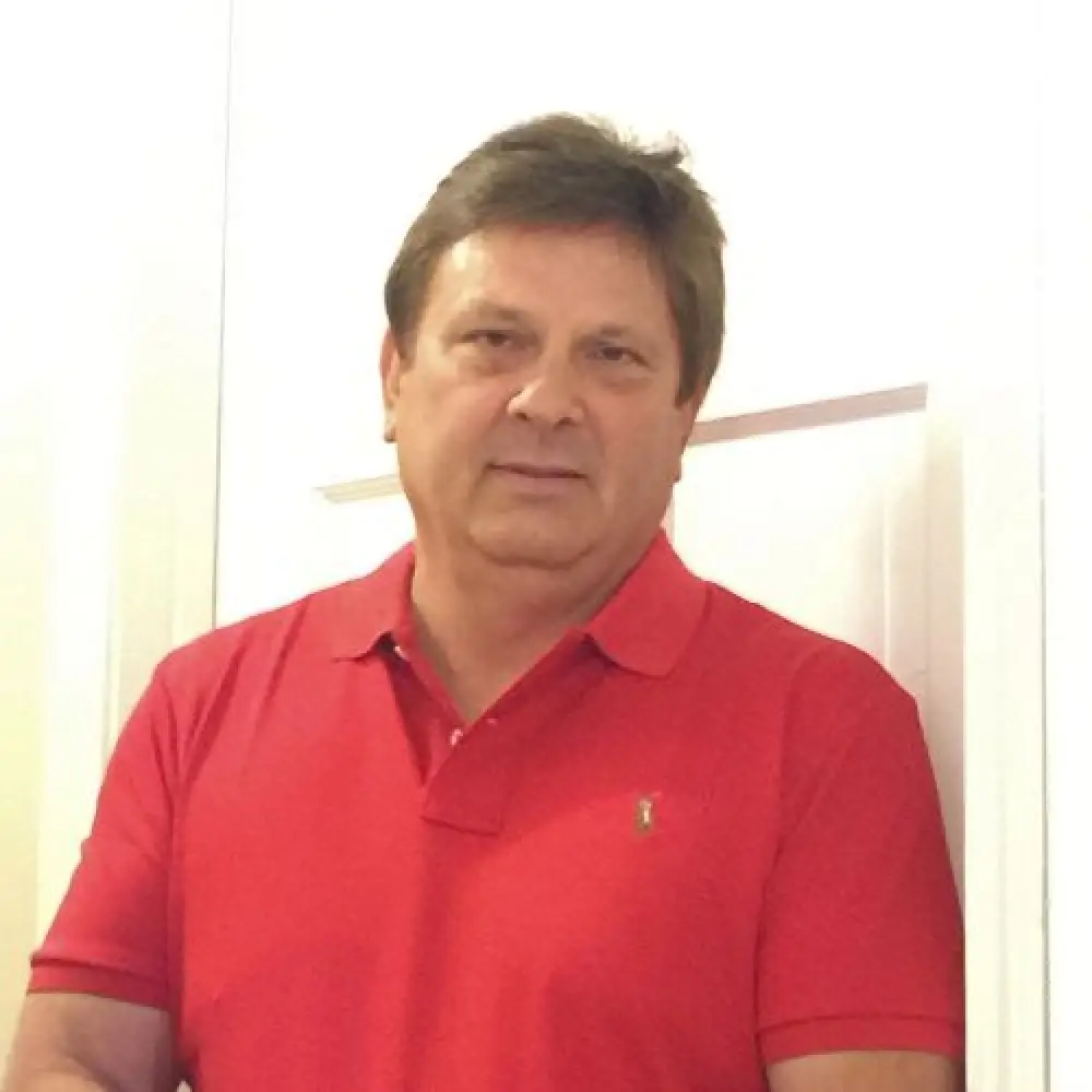 Person wearing a red polo shirt stands in front of a white door.