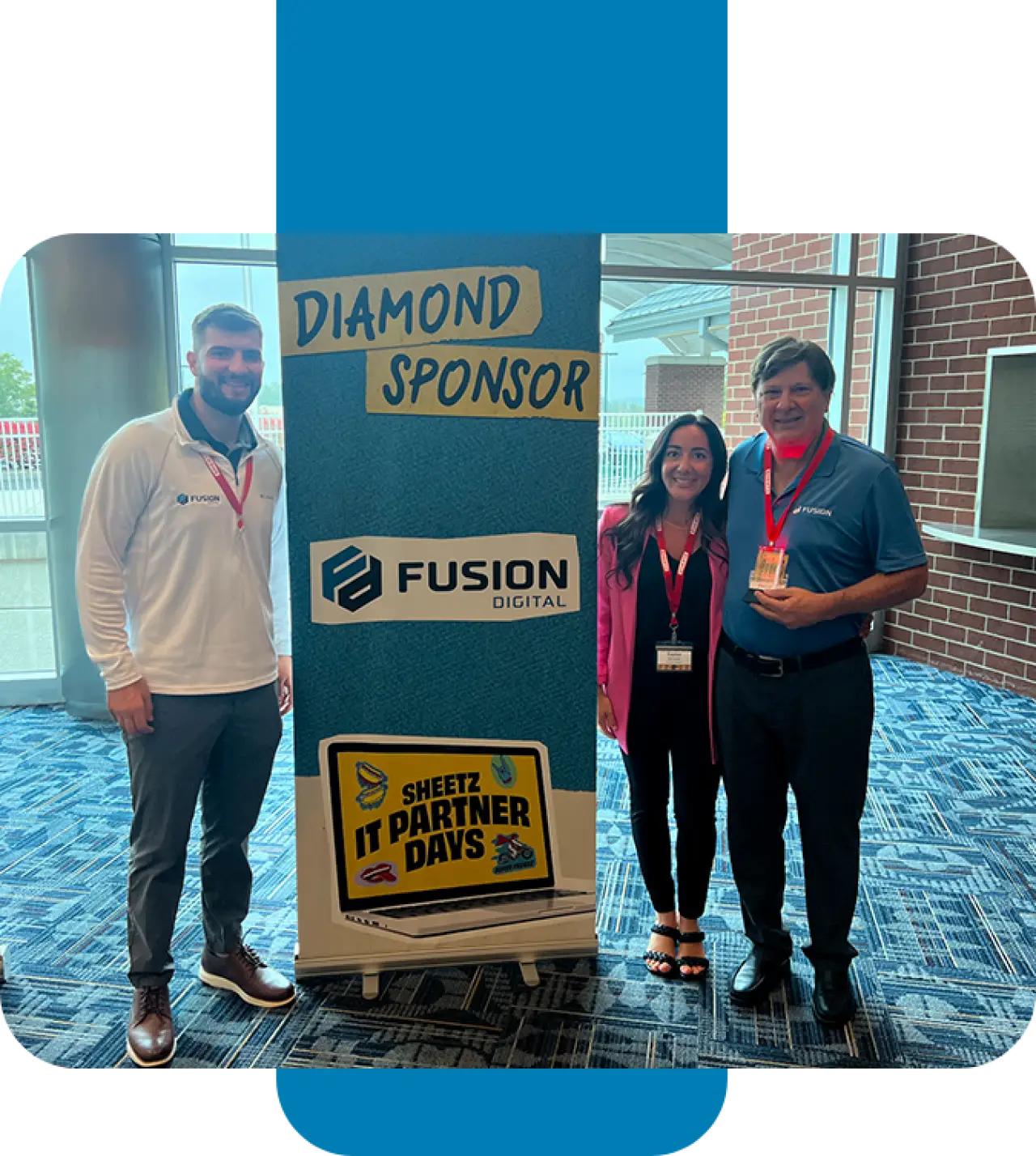 Three people stand by a sign for Fusion Digital, a diamond sponsor at IT Partner Days.