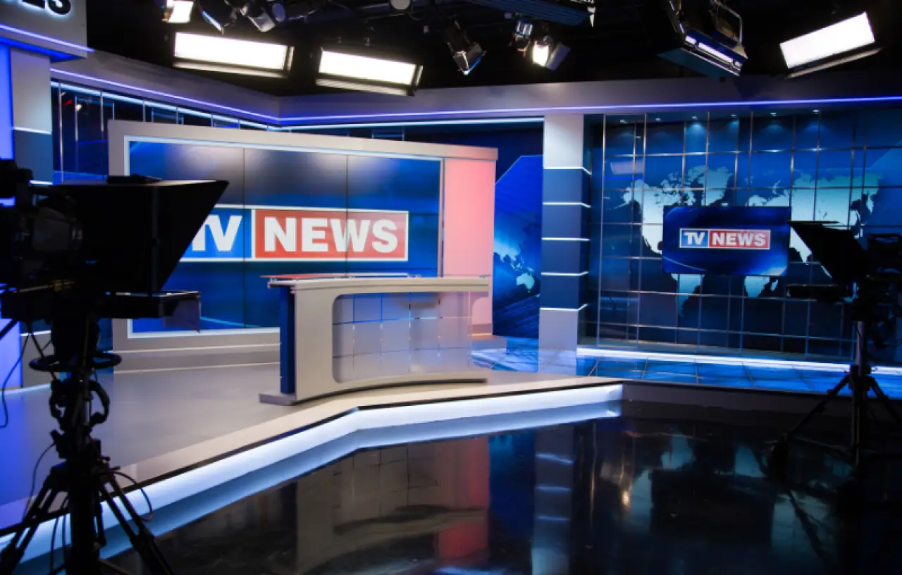 Modern TV news studio with bright lights, cameras, and a world map on the digital screen.