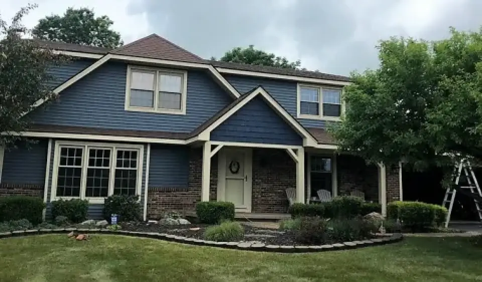 Two-story house with blue siding, brick accents, and a well-manicured front yard.