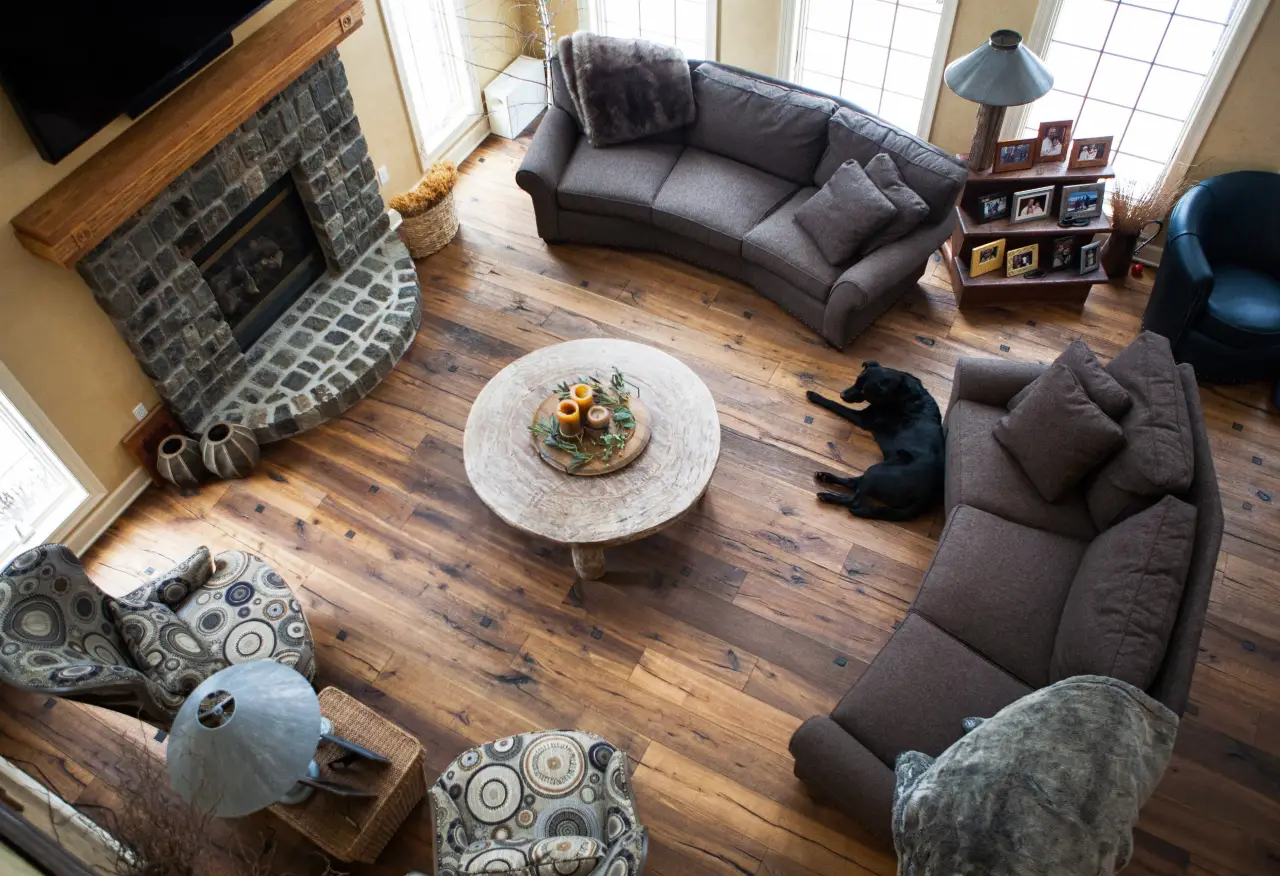 A cozy living room featuring a stone fireplace, circular coffee table with decor, and a black dog resting on the floor.