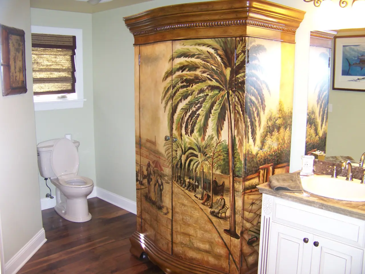 A bathroom featuring a decorative shower enclosure with palm tree artwork, a toilet, and a sink with a countertop.