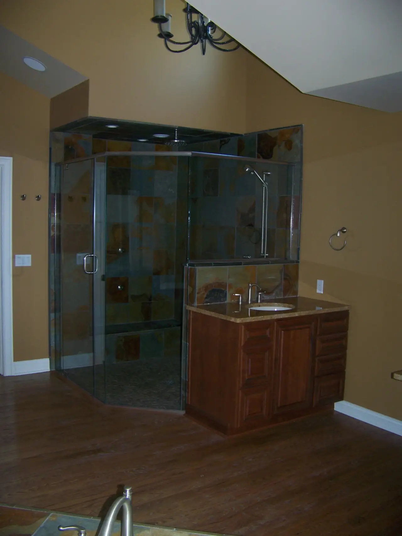 A modern bathroom featuring a glass shower, wooden vanity, and earthy-toned walls.