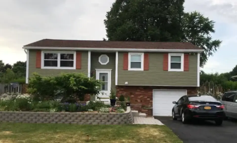 Two-story suburban house with a car parked in the driveway and a landscaped front yard.