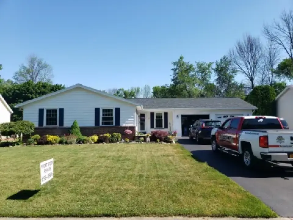 Single-story house with a well-kept lawn and two trucks parked in the driveway.