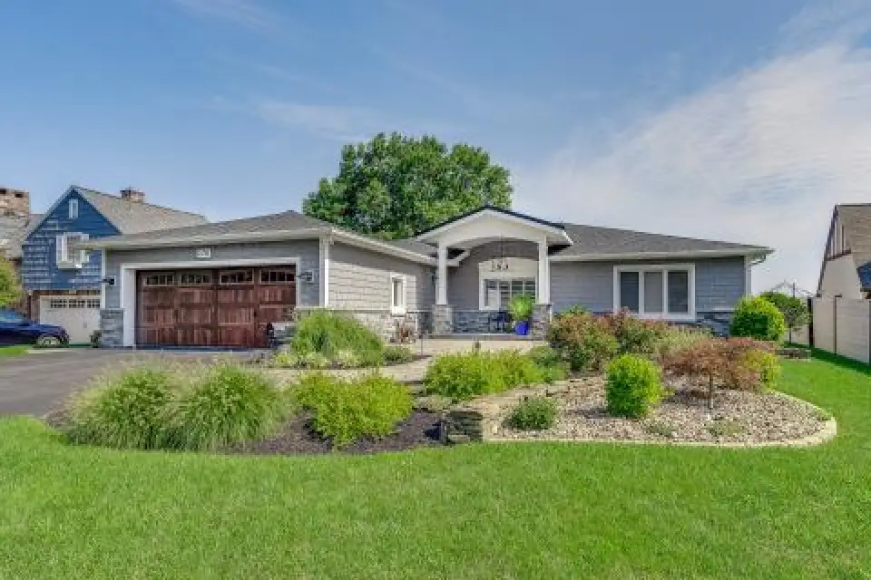 Single-story house with gray siding, wooden garage doors, and landscaped front yard.