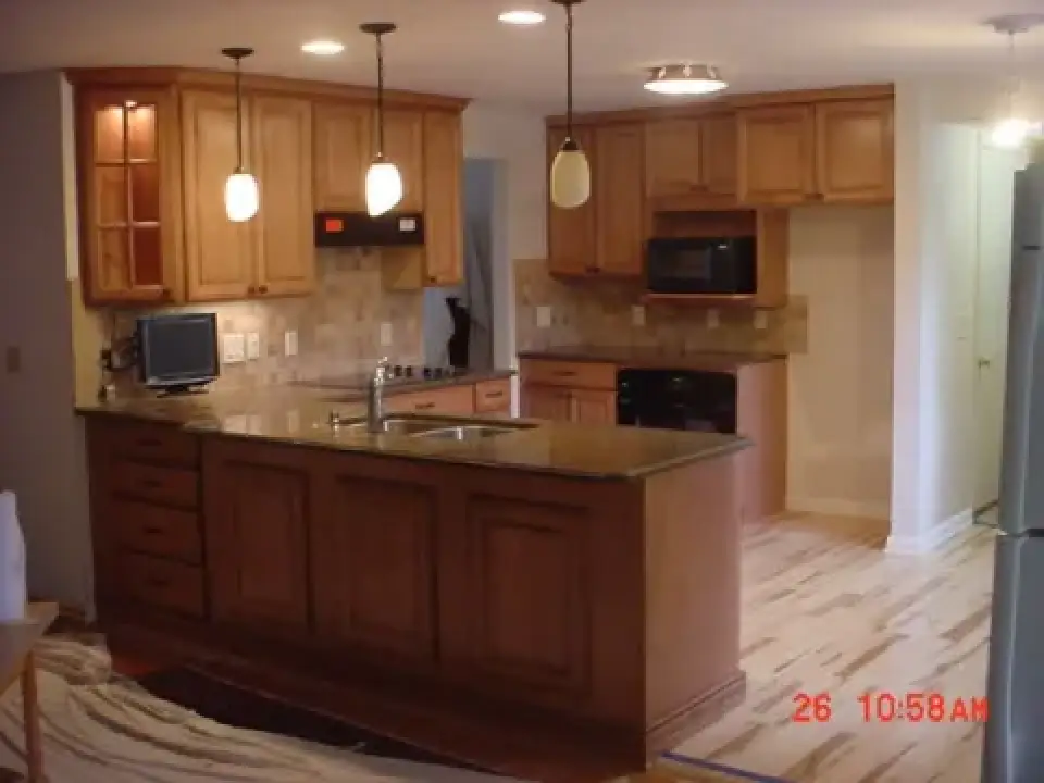 Modern kitchen with wooden cabinets, island sink, pendant lights, and built-in appliances.