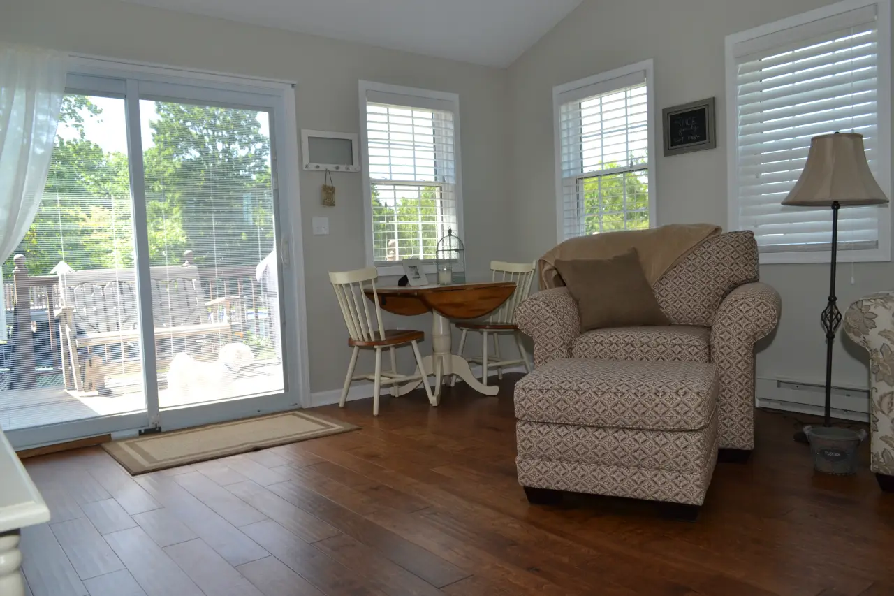 A cozy living space featuring a patterned armchair, a small dining table, and large sliding doors leading to a deck.