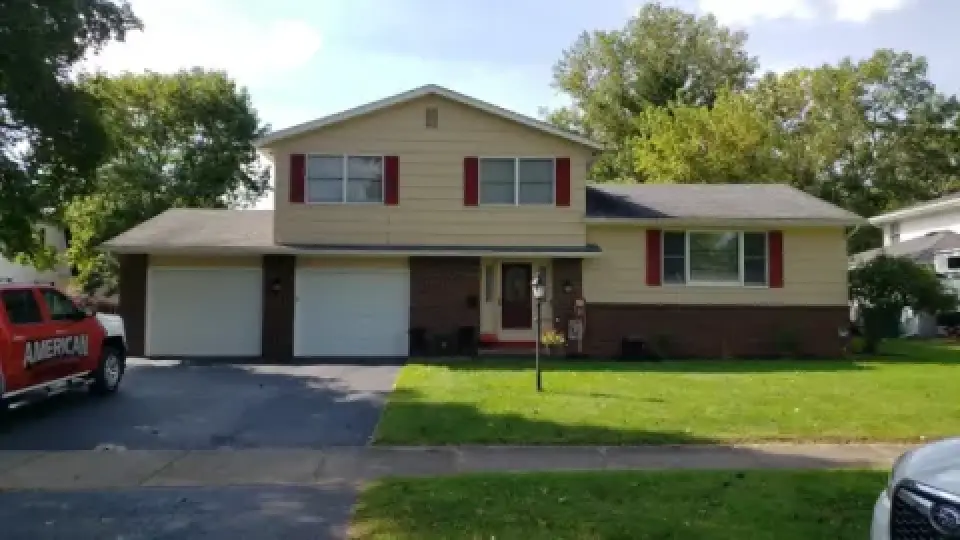 Two-story suburban house with red shutters, double garage, and a red truck parked outside.