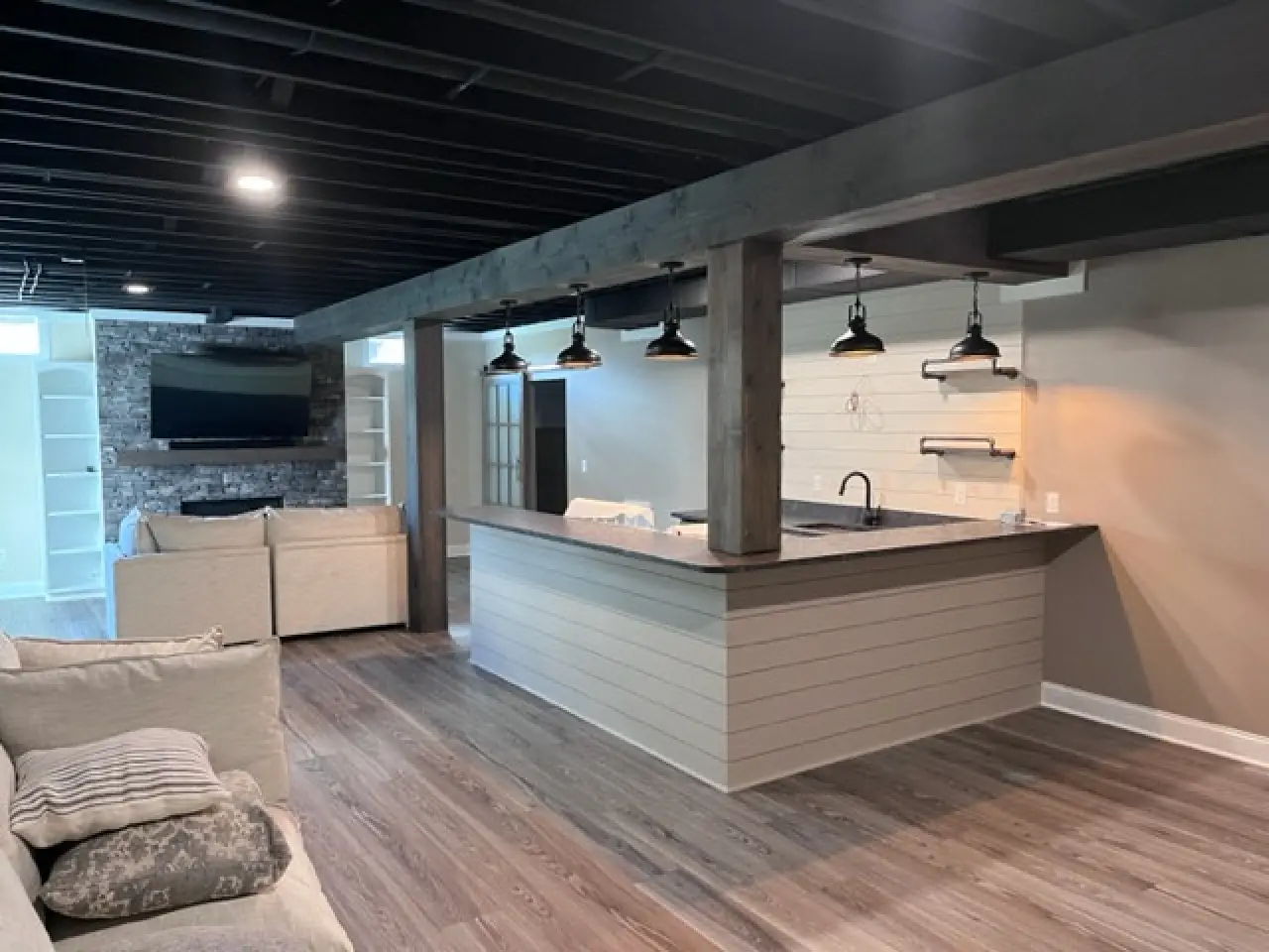A modern, open-concept living space featuring a kitchen island, pendant lights, and a cozy seating area with a TV.