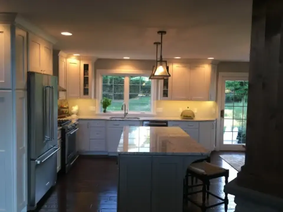 Bright, modern kitchen with island, white cabinets, stainless appliances, and large window.