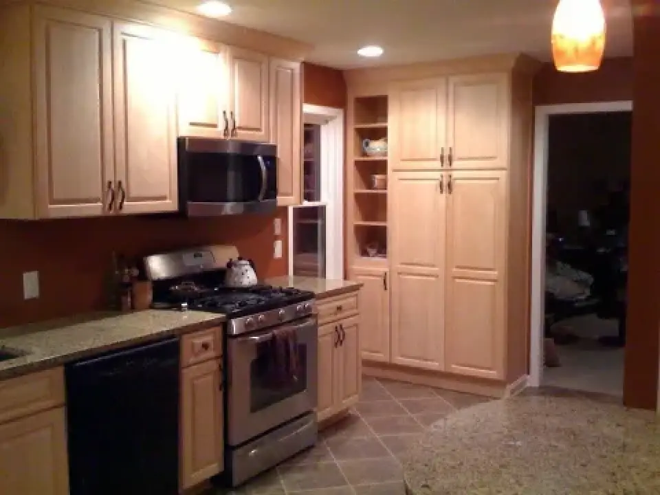Modern kitchen with light wood cabinets, stainless steel appliances, and granite countertops.