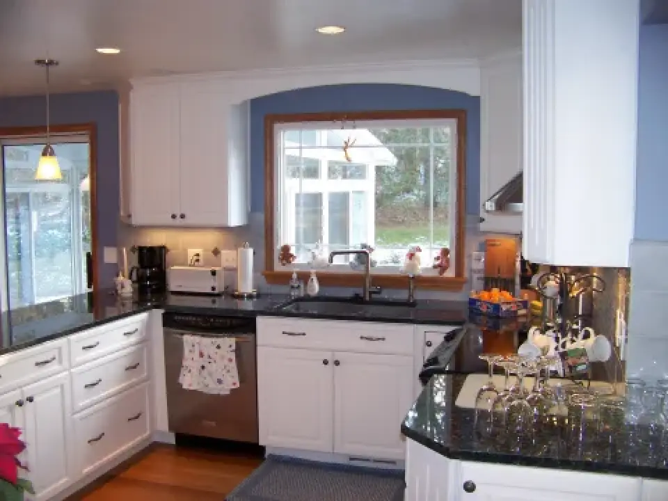 Modern kitchen with white cabinets, black countertops, and a window above the sink.