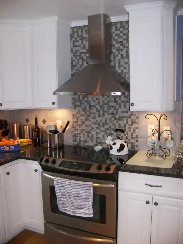 Modern kitchen with white cabinets, a stainless steel stove, and a checkered backsplash.