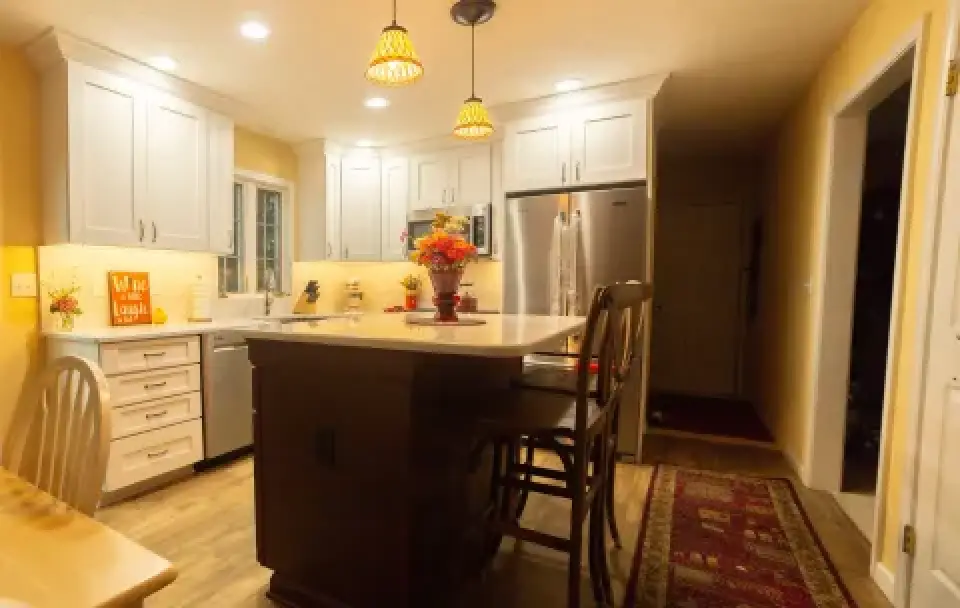 Bright kitchen with white cabinets, island, pendant lights, and autumn-themed decorations.