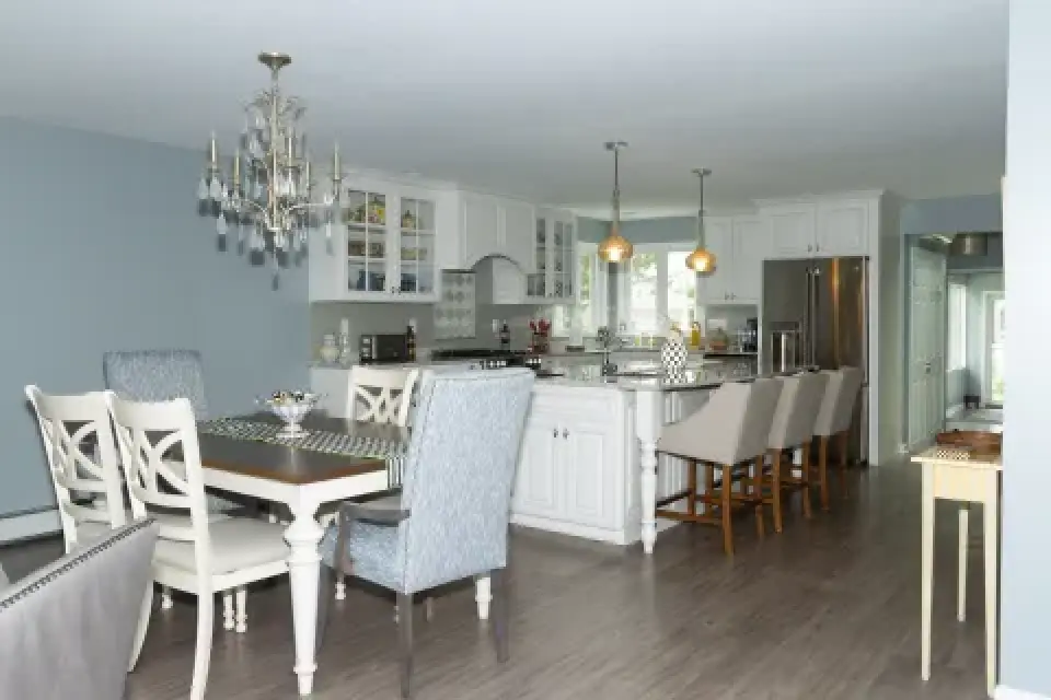 Bright, modern kitchen with dining table, chandelier, island seating, and stainless appliances.