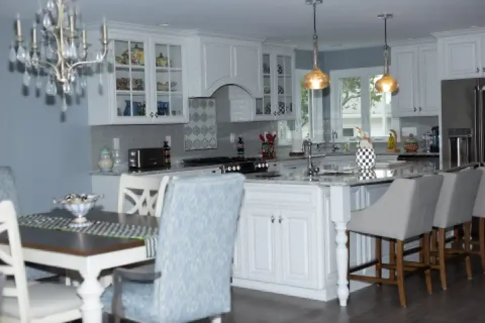 Modern kitchen with white cabinets, pendant lights, and a dining table with upholstered chairs.