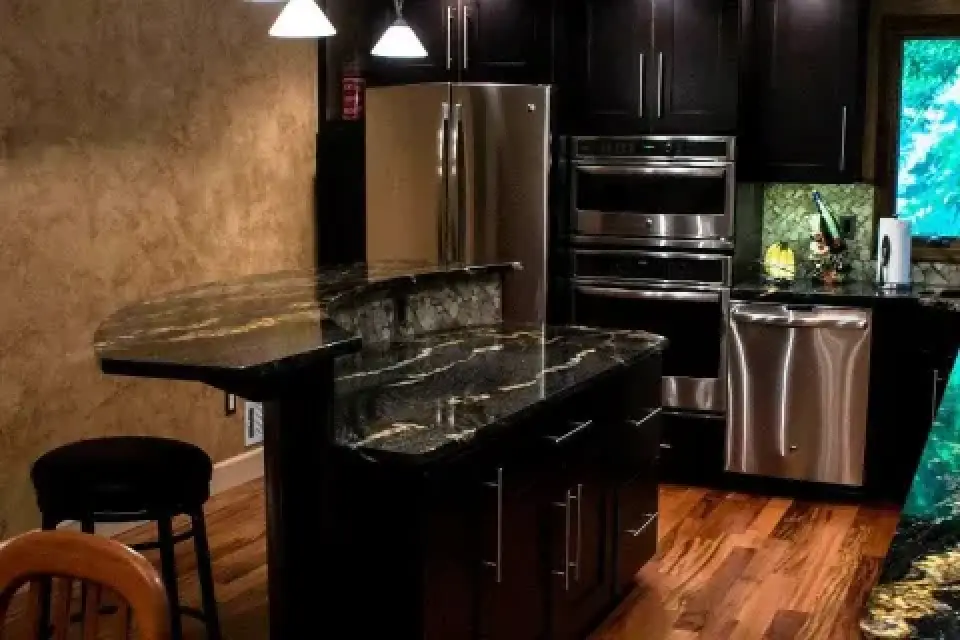 Modern kitchen with dark cabinets, stainless steel appliances, and black granite countertops.