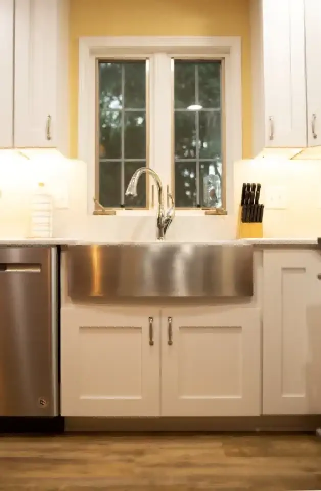 Bright kitchen with a large farmhouse sink, white cabinets, and a window above the sink.