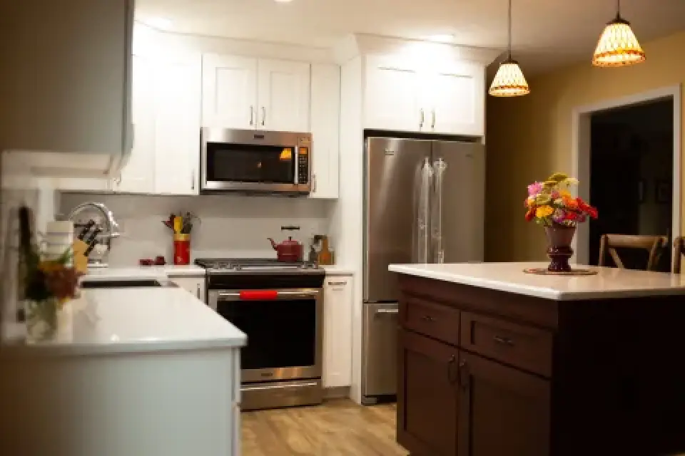 Modern kitchen with white cabinets, stainless steel appliances, and a flower vase on the island.