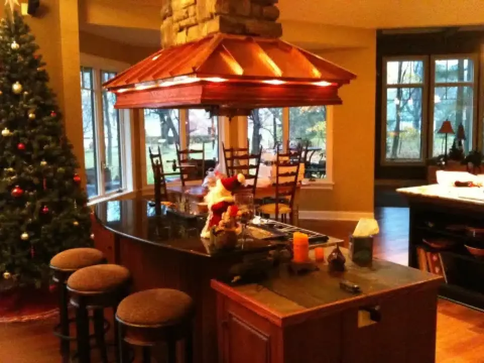 Cozy kitchen with a decorated Christmas tree, island seating, and a copper range hood.