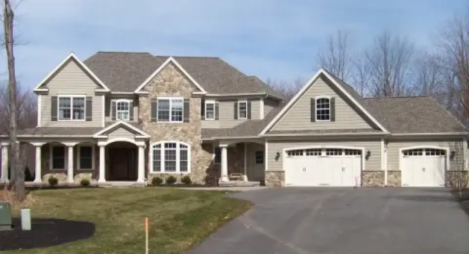 Large two-story suburban house with stone accents, front porch, and attached three-car garage.