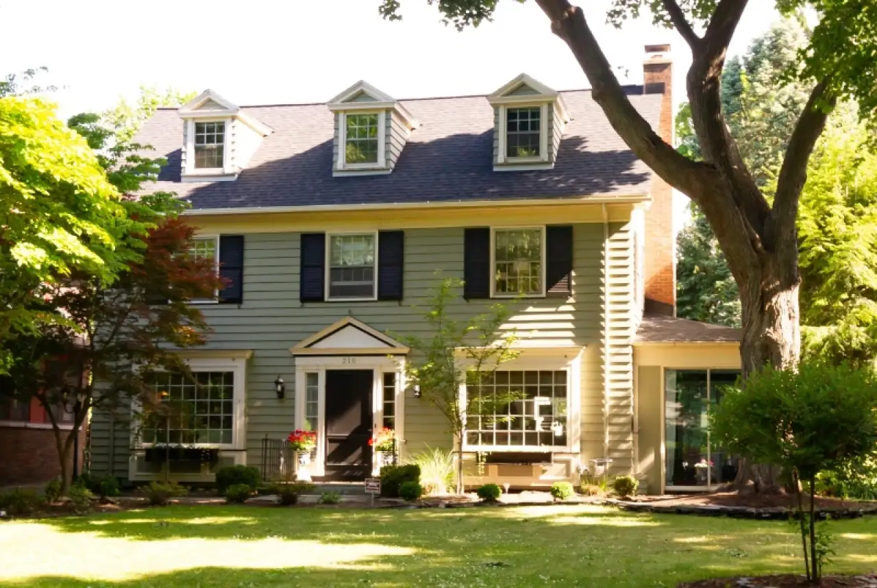 A two-story suburban house with gray siding, black shutters, and a well-kept front yard.