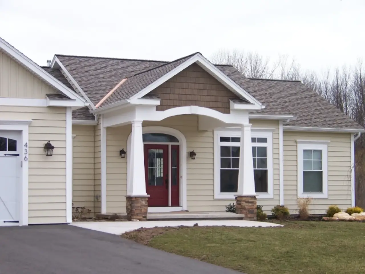 Single-story beige house with a red front door, white trim, and a covered entry porch.