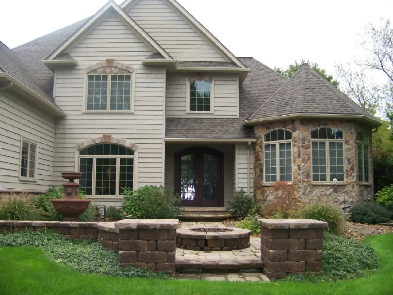 Two-story suburban house with stone and siding exterior, front steps, and landscaped yard.