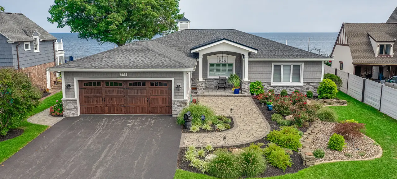 The exterior of the front of a house showing a garage and garden.